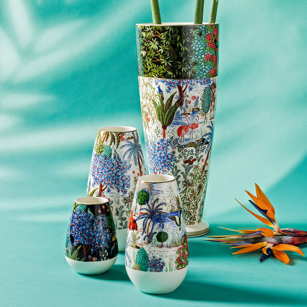 Quatre vases avec des motifs colorés de jungle et d'animaux, dont des flamants roses et des plantes exotiques, sur fond turquoise.